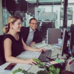 photo of man and woman looking at computer