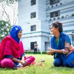 photo of women sitting on grass talking